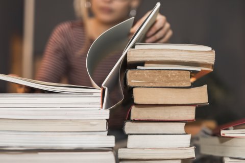 Student reading book from stack